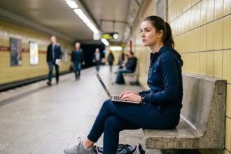 Jeune femme en tenue de sport au métro, ordinateur portable